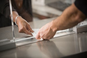 A hand passing a check through a payment window