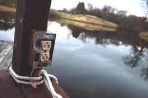 Old exposed outlet on a dock by a lake