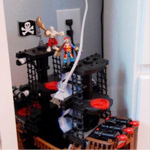 White electric cord hanging down over toy pirate ship and pirate action figures