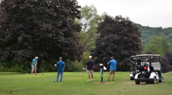 A golf foursome playing a round of golf with two golf carts nearby