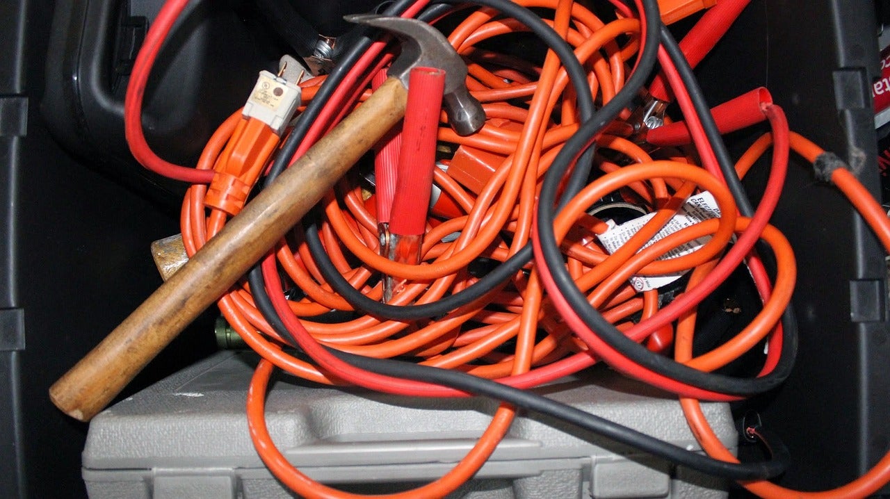 A jumble of extension cords, jumper cables, and a hammer.