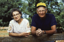 An elderly couple leaning on a fence