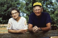 An elderly couple leaning on a fence